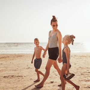 Smiling Mom and her kids walking along a sandy beach