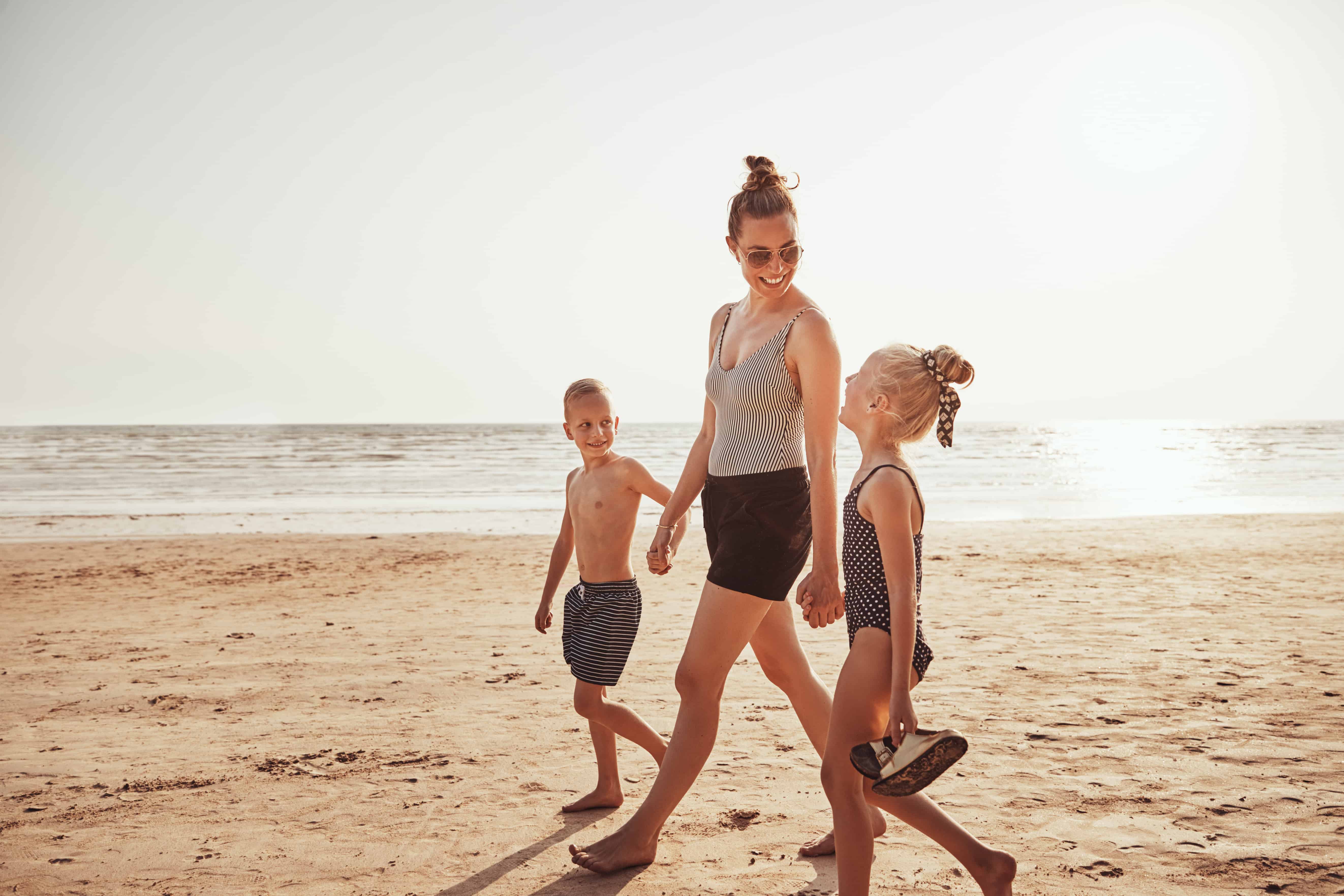 Smiling Mom and her kids walking along a sandy beach